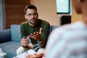 Young man having counseling with mental health professional in office.